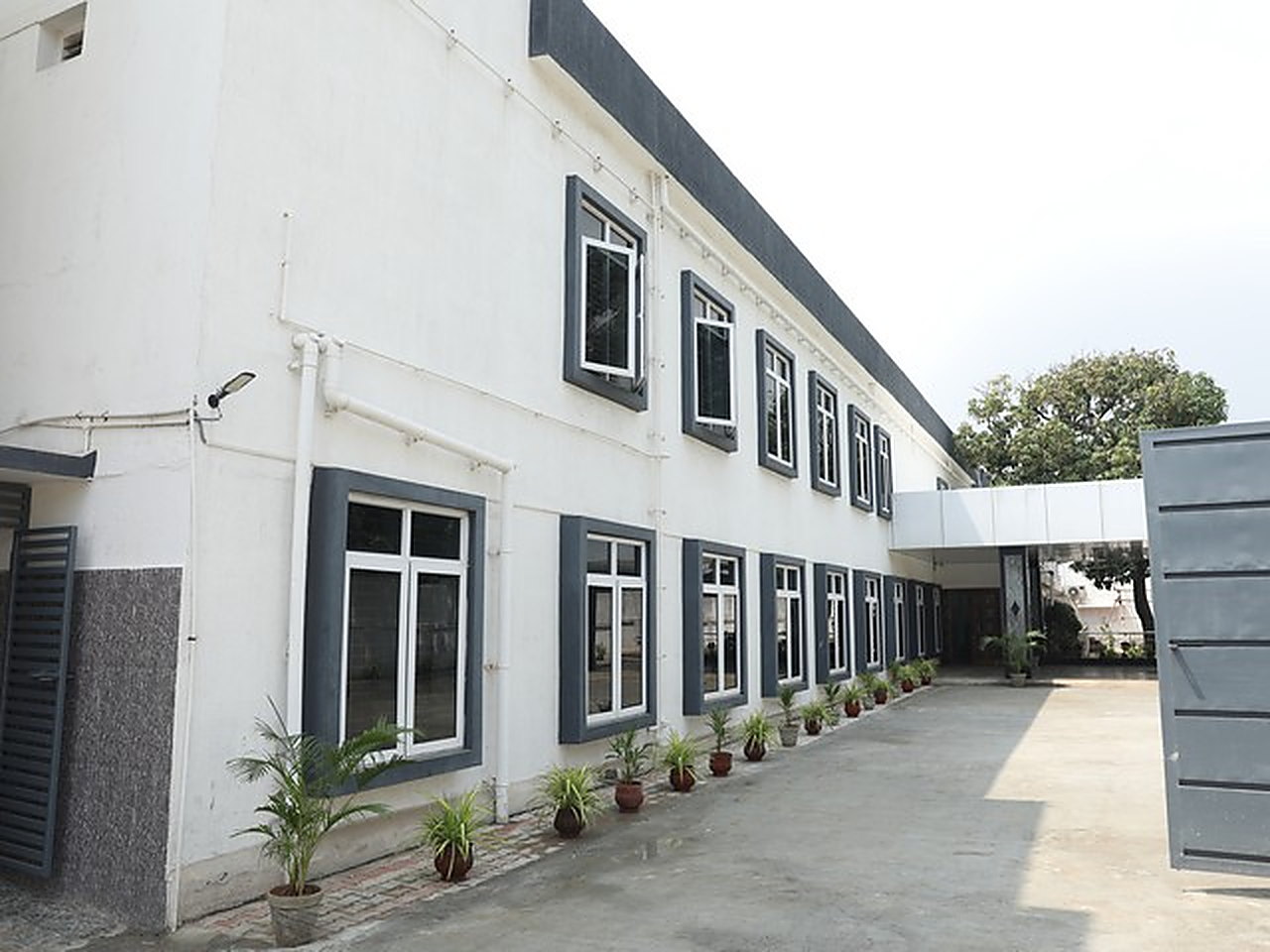 The side elevation of the school building, potted plants along the path